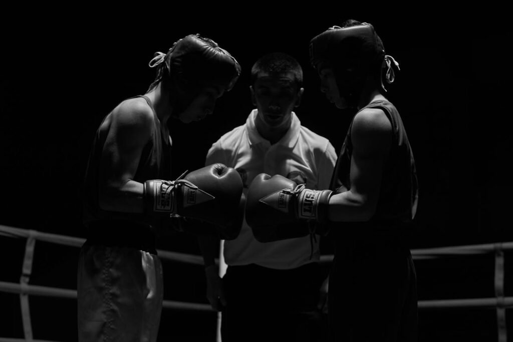 Two boxers face off in a dimly lit ring under a referee's watchful eye in Lautaro, Chile.